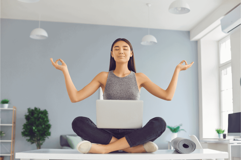 woman sat on floor in yoga pose with laptop on lap