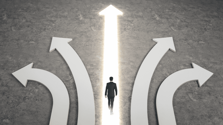 An image of a man walking towards a lit up arrow with other arrows going in different directions. This is being used to indicate that when you overcome overwhelm and follow the right path will be easier to find success