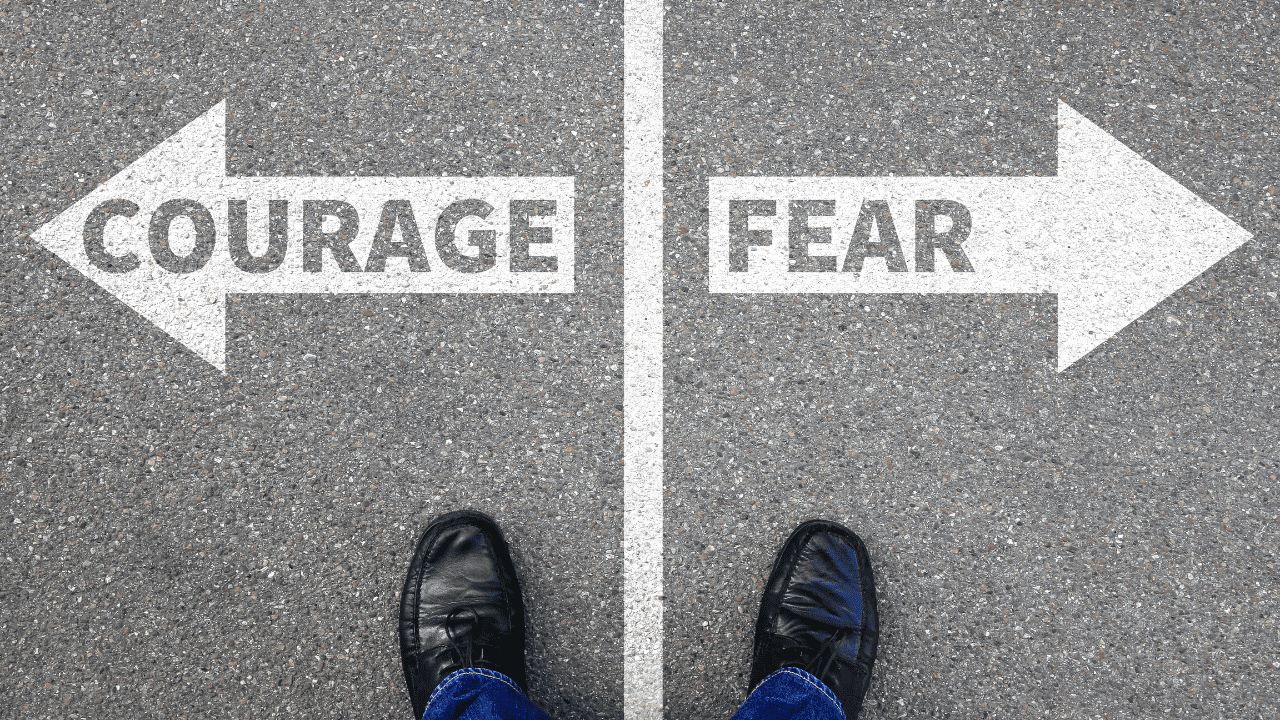 Self confidence. Image of a person standing two feet showing. Stood on grey concrete with a white line on the ground dividing it with the word "courage" on the left and "fear" on the right. Depicting what you will choose. Confidence and courage or fear