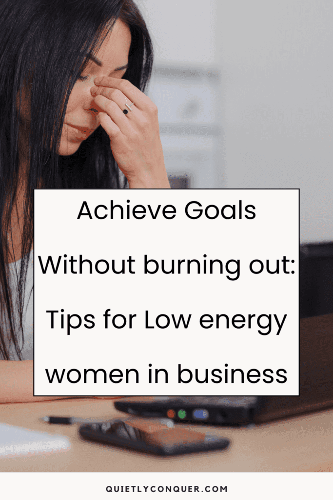 A woman sat at desk looking tired with her fingers each side of her nose, eyes closed. The text "Achieve Goals Without Burning Out: Tips for Low Energy Women in Business" in front of the image
